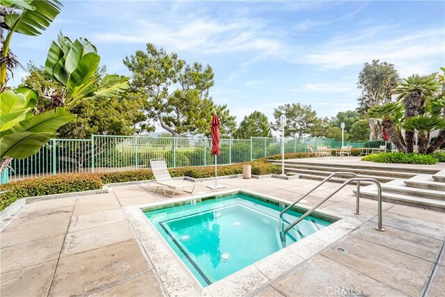 view of swimming pool with a hot tub and a patio area