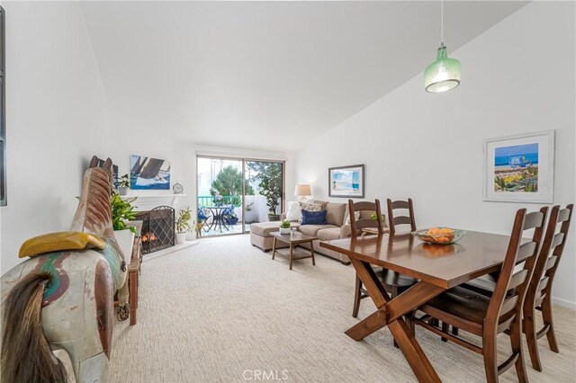 carpeted dining area featuring high vaulted ceiling