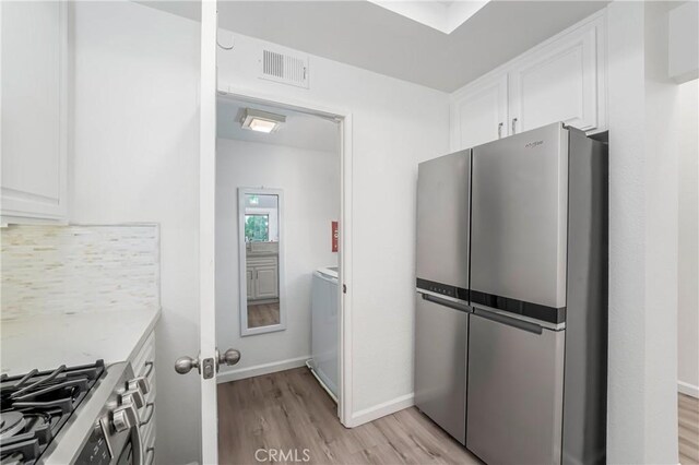 kitchen featuring white cabinetry, decorative backsplash, light wood-type flooring, and appliances with stainless steel finishes