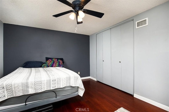 bedroom featuring ceiling fan, dark hardwood / wood-style floors, a closet, and a textured ceiling