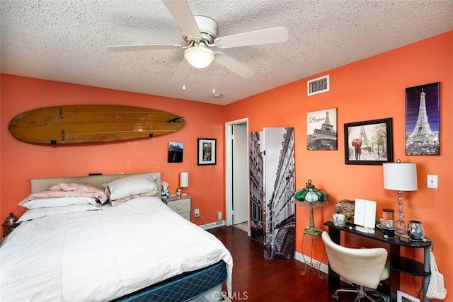 bedroom featuring dark hardwood / wood-style flooring, ceiling fan, and a textured ceiling