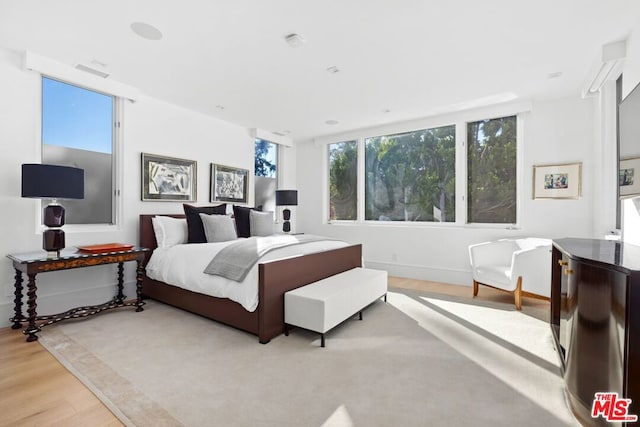 bedroom with multiple windows and light wood-type flooring