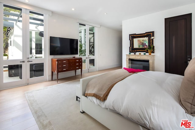 bedroom featuring access to exterior, light hardwood / wood-style floors, and french doors