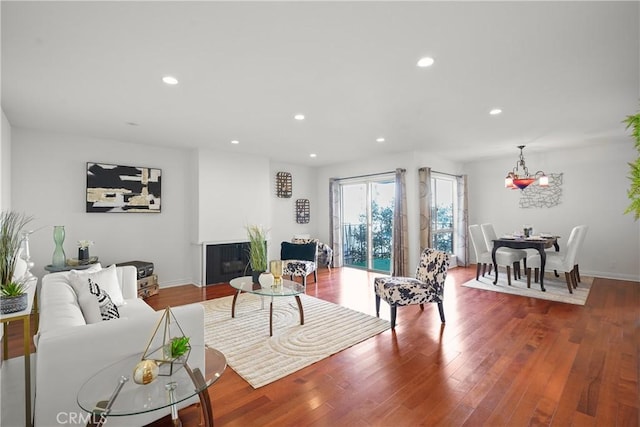 living room featuring recessed lighting, baseboards, a glass covered fireplace, and wood finished floors