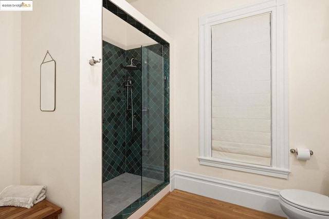 bathroom featuring hardwood / wood-style flooring, a tile shower, and toilet