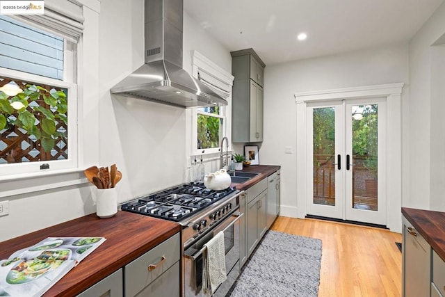 kitchen with gray cabinets, wood counters, sink, exhaust hood, and stainless steel appliances