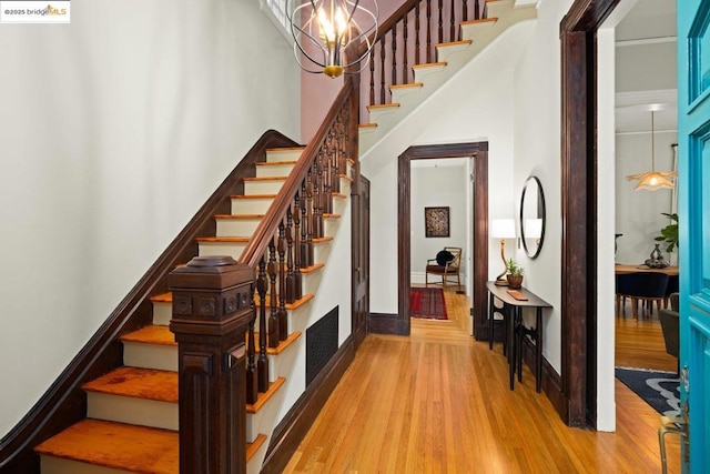 stairs featuring an inviting chandelier and wood-type flooring