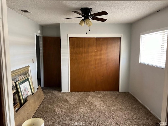 unfurnished bedroom featuring a textured ceiling, a closet, and dark colored carpet