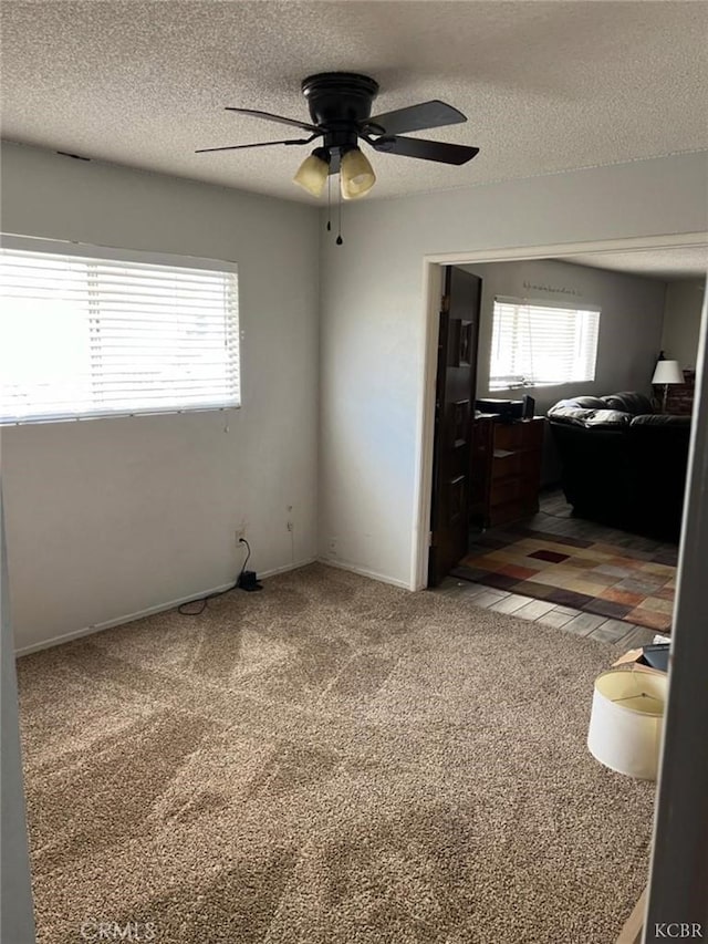 carpeted bedroom featuring multiple windows, ceiling fan, and a textured ceiling