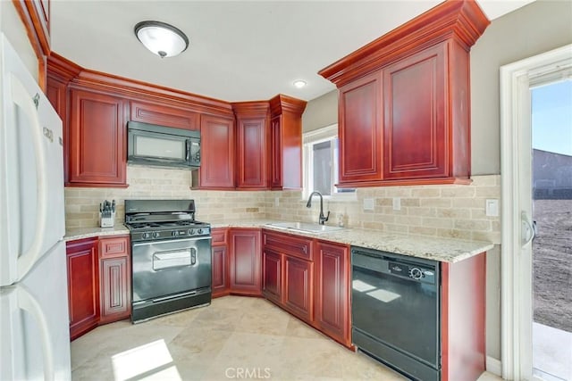 kitchen featuring a wealth of natural light, light stone countertops, sink, and black appliances