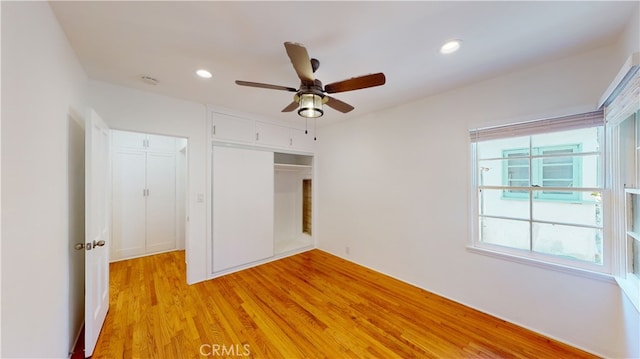 unfurnished bedroom with ceiling fan, light wood-type flooring, and a closet