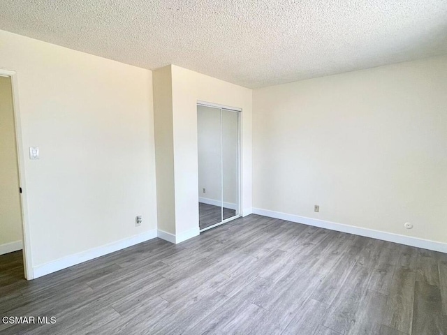 unfurnished bedroom with a textured ceiling, dark hardwood / wood-style flooring, and a closet