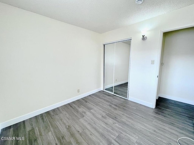 unfurnished bedroom with wood-type flooring, a textured ceiling, and a closet