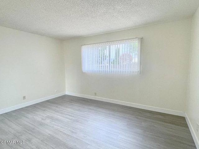 empty room with hardwood / wood-style flooring and a textured ceiling