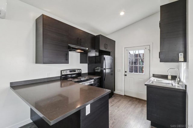 kitchen featuring sink, kitchen peninsula, black fridge, light wood-type flooring, and stainless steel electric range