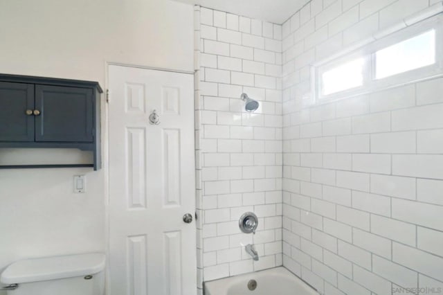 bathroom with toilet and tiled shower / bath