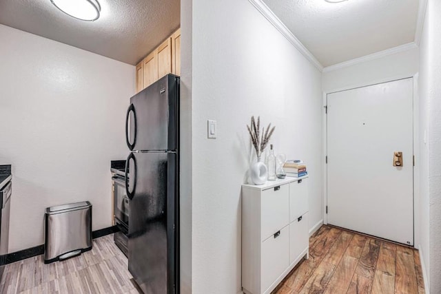 kitchen with stove, crown molding, black fridge, a textured ceiling, and light hardwood / wood-style flooring