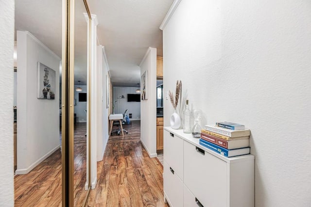 hall featuring ornamental molding and light hardwood / wood-style floors