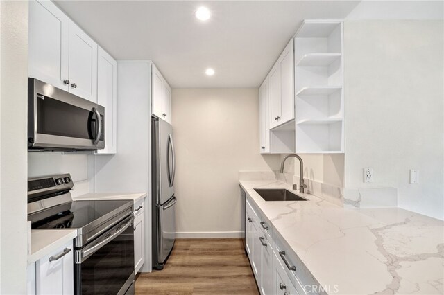 kitchen with white cabinetry, appliances with stainless steel finishes, sink, and light stone counters