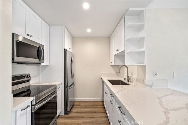 kitchen featuring white cabinetry, appliances with stainless steel finishes, sink, and light stone counters