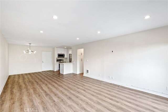 unfurnished living room featuring a chandelier and light wood-type flooring