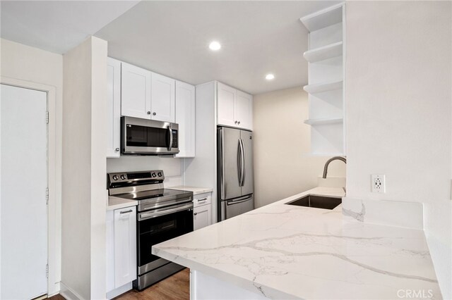 kitchen featuring sink, white cabinets, stainless steel appliances, light stone countertops, and light wood-type flooring