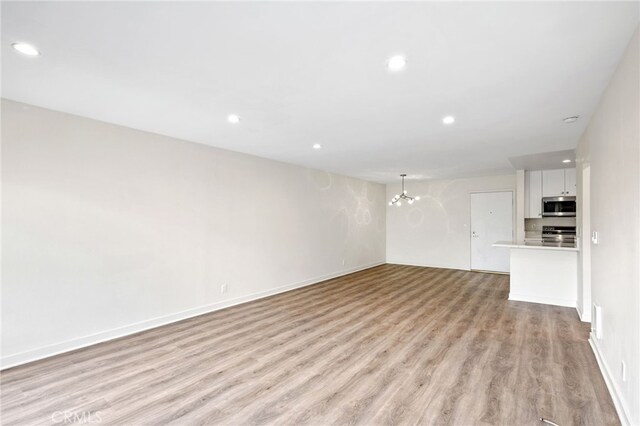 unfurnished living room with a chandelier and light wood-type flooring