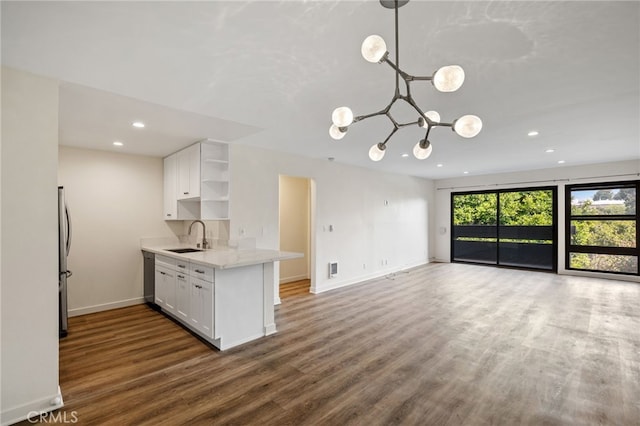 kitchen featuring dark wood-type flooring, sink, hanging light fixtures, appliances with stainless steel finishes, and white cabinets