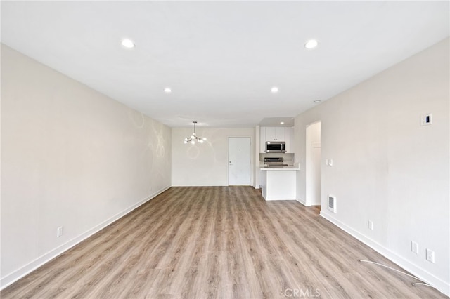 unfurnished living room featuring a notable chandelier and light hardwood / wood-style floors