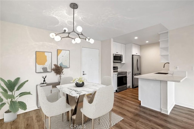 dining area featuring dark wood-type flooring, a chandelier, and sink