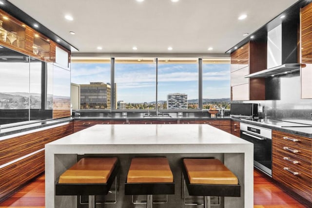 kitchen featuring hardwood / wood-style flooring, a center island, a breakfast bar area, and stainless steel oven