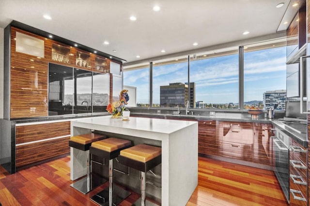 kitchen with a breakfast bar, sink, stainless steel oven, a center island, and light wood-type flooring