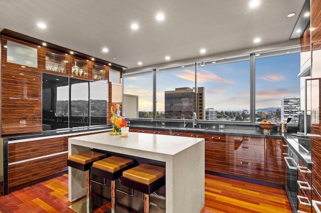 kitchen featuring cooktop, a breakfast bar, sink, light wood-type flooring, and a kitchen island