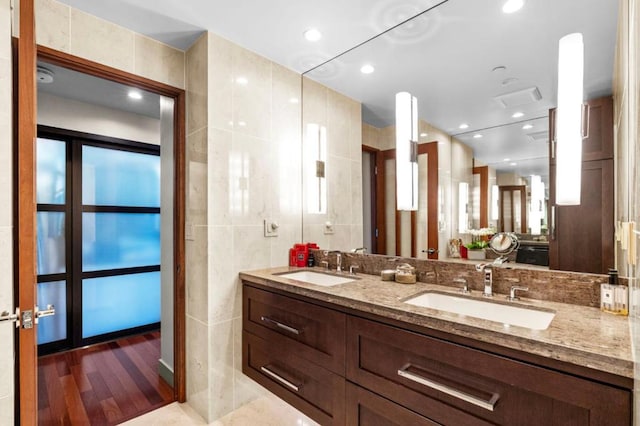 bathroom featuring vanity, wood-type flooring, and tile walls