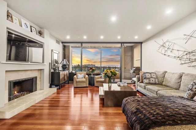 living room featuring a tile fireplace, floor to ceiling windows, and wood-type flooring