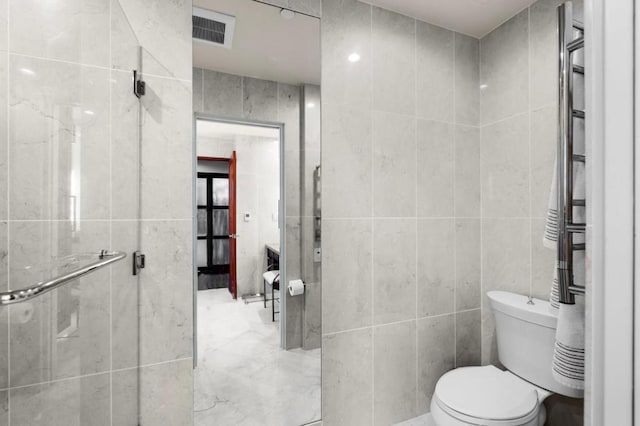 bathroom featuring tile walls, a shower with shower door, and toilet