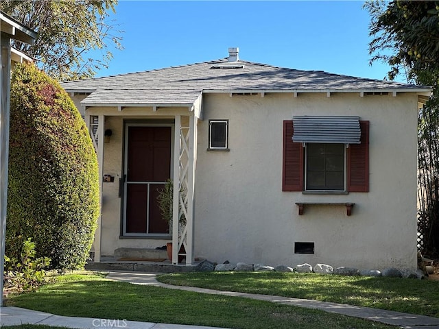 view of exterior entry featuring a lawn