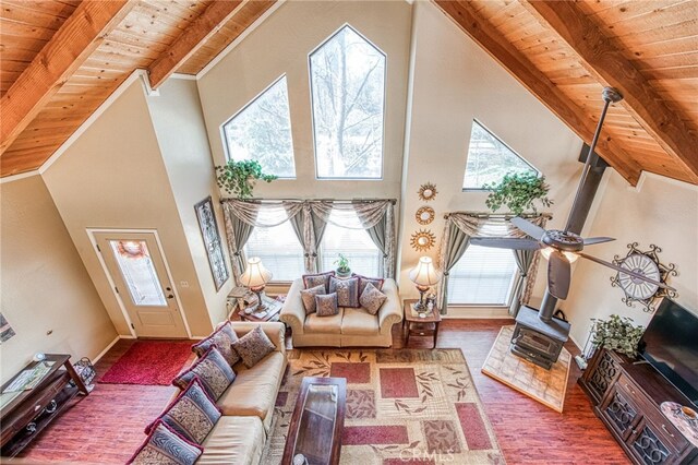 living room featuring high vaulted ceiling, a wood stove, wooden ceiling, and beam ceiling