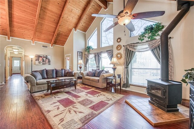 living room with a healthy amount of sunlight, a wood stove, hardwood / wood-style floors, and beam ceiling