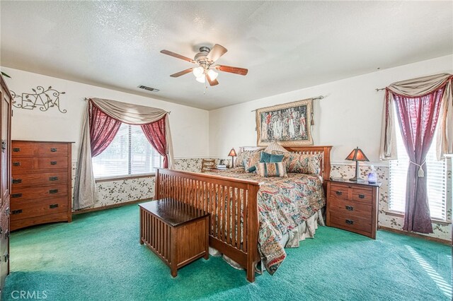 carpeted bedroom with ceiling fan and a textured ceiling