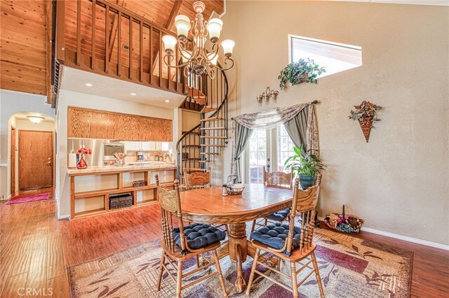 dining area with hardwood / wood-style flooring, a notable chandelier, wood ceiling, and a high ceiling