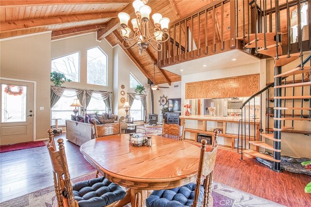 dining area featuring hardwood / wood-style flooring, wooden ceiling, an inviting chandelier, and a wood stove