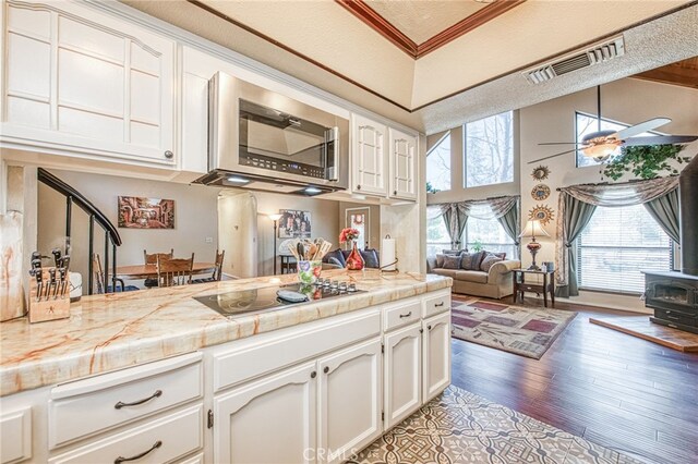 kitchen with a wood stove, black electric cooktop, ceiling fan, light hardwood / wood-style floors, and white cabinets