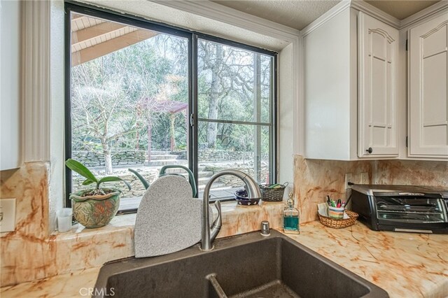 kitchen with tasteful backsplash, sink, and white cabinets