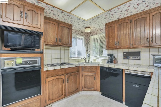 kitchen featuring tasteful backsplash, sink, tile counters, and black appliances