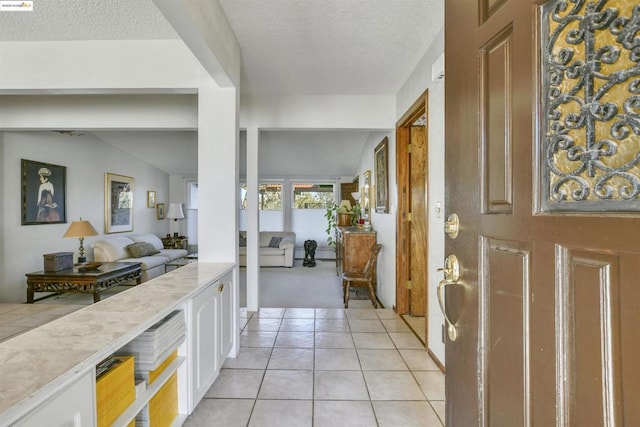 entryway featuring lofted ceiling, light tile patterned floors, and a textured ceiling