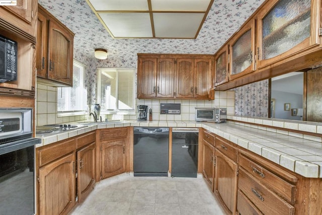 kitchen featuring tile counters, light tile patterned floors, decorative backsplash, and black appliances