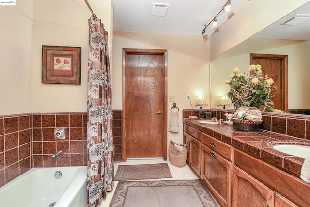 bathroom with vanity, a bath, tile patterned floors, and tile walls