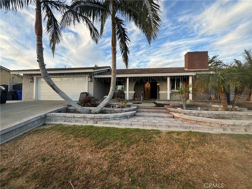 view of front of property featuring a front lawn, driveway, an attached garage, and stucco siding