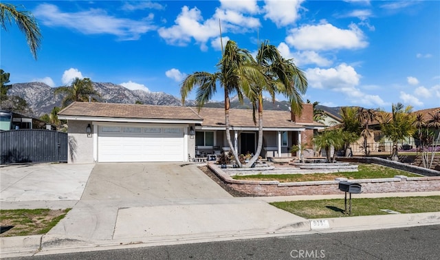 ranch-style home with concrete driveway, a mountain view, an attached garage, and stucco siding